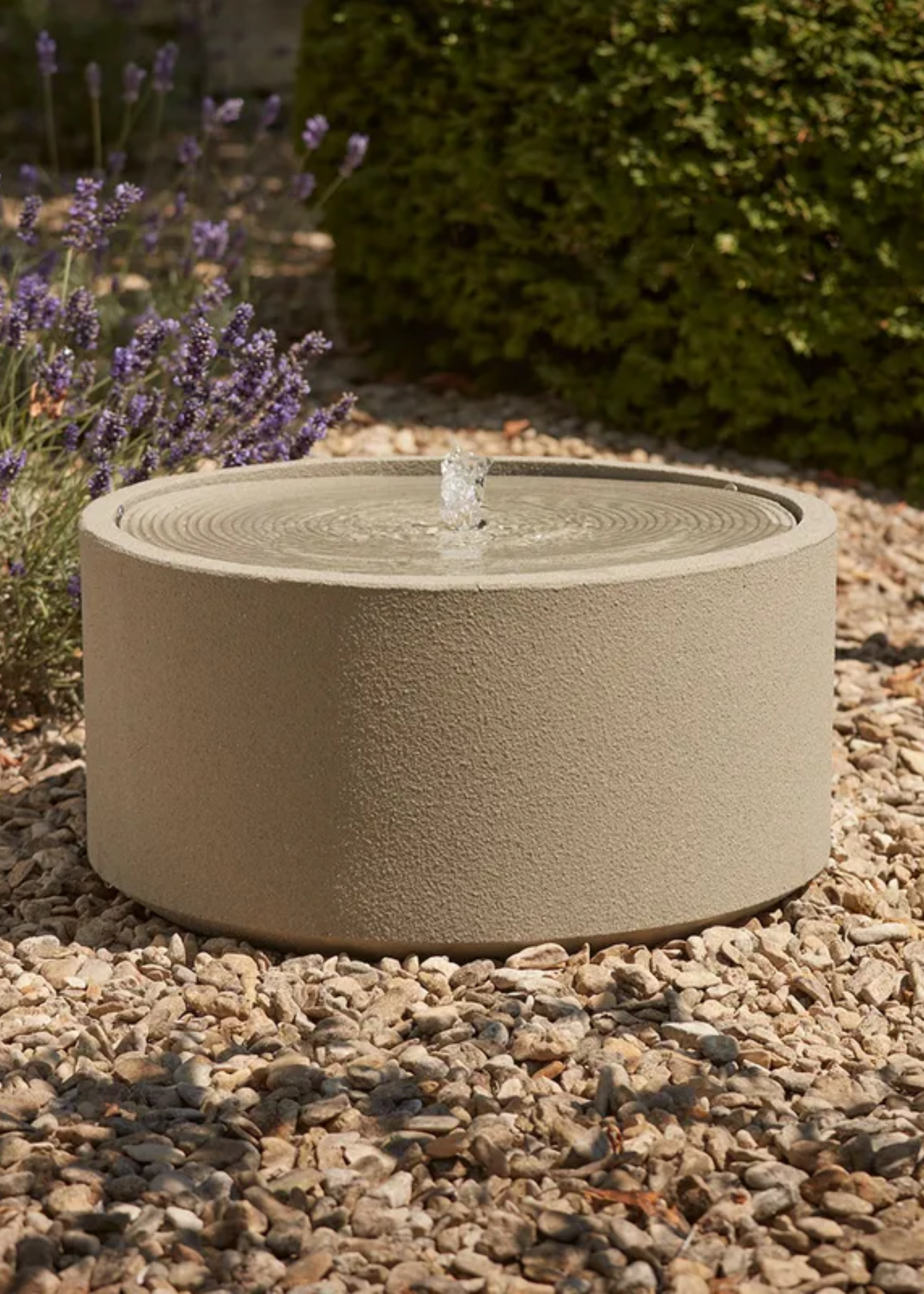 A textured outdoor water feature on gravel