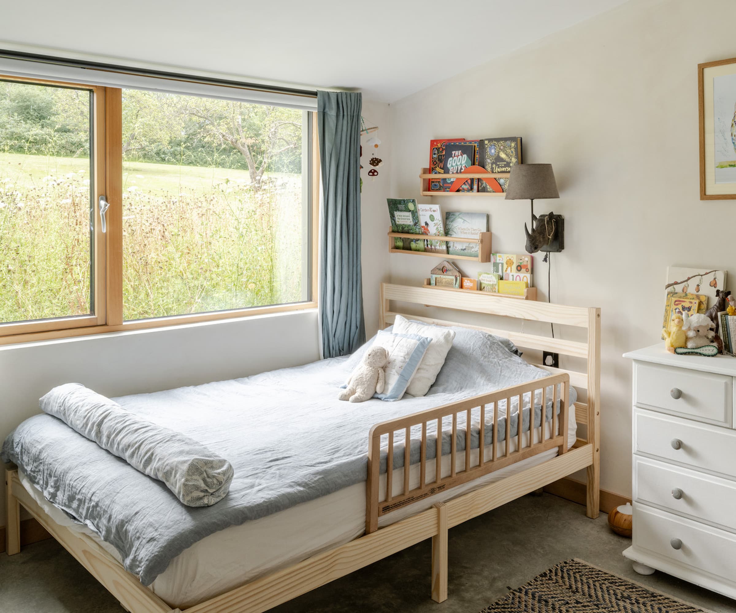 A children's bedroom with a large window with a blue curtain