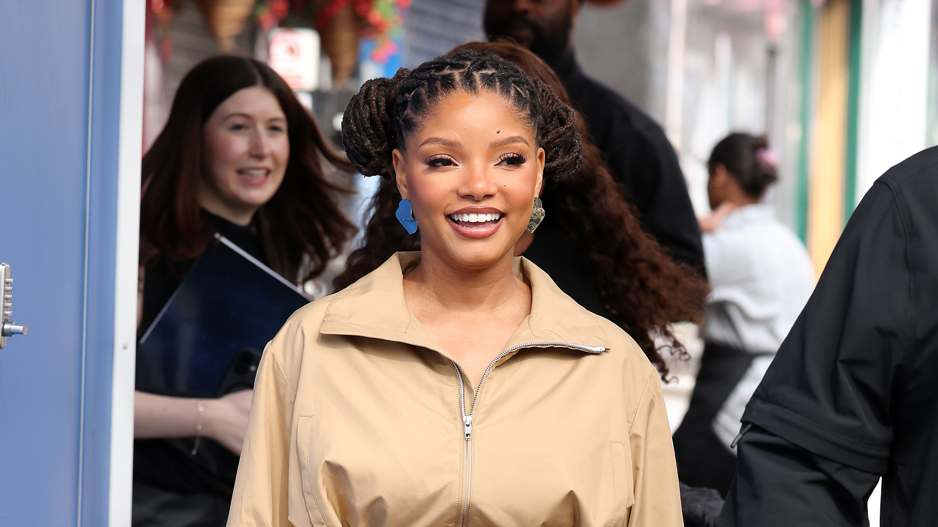 Halle Bailey wearing a tan jacket and matching skirt with white heel sandals 