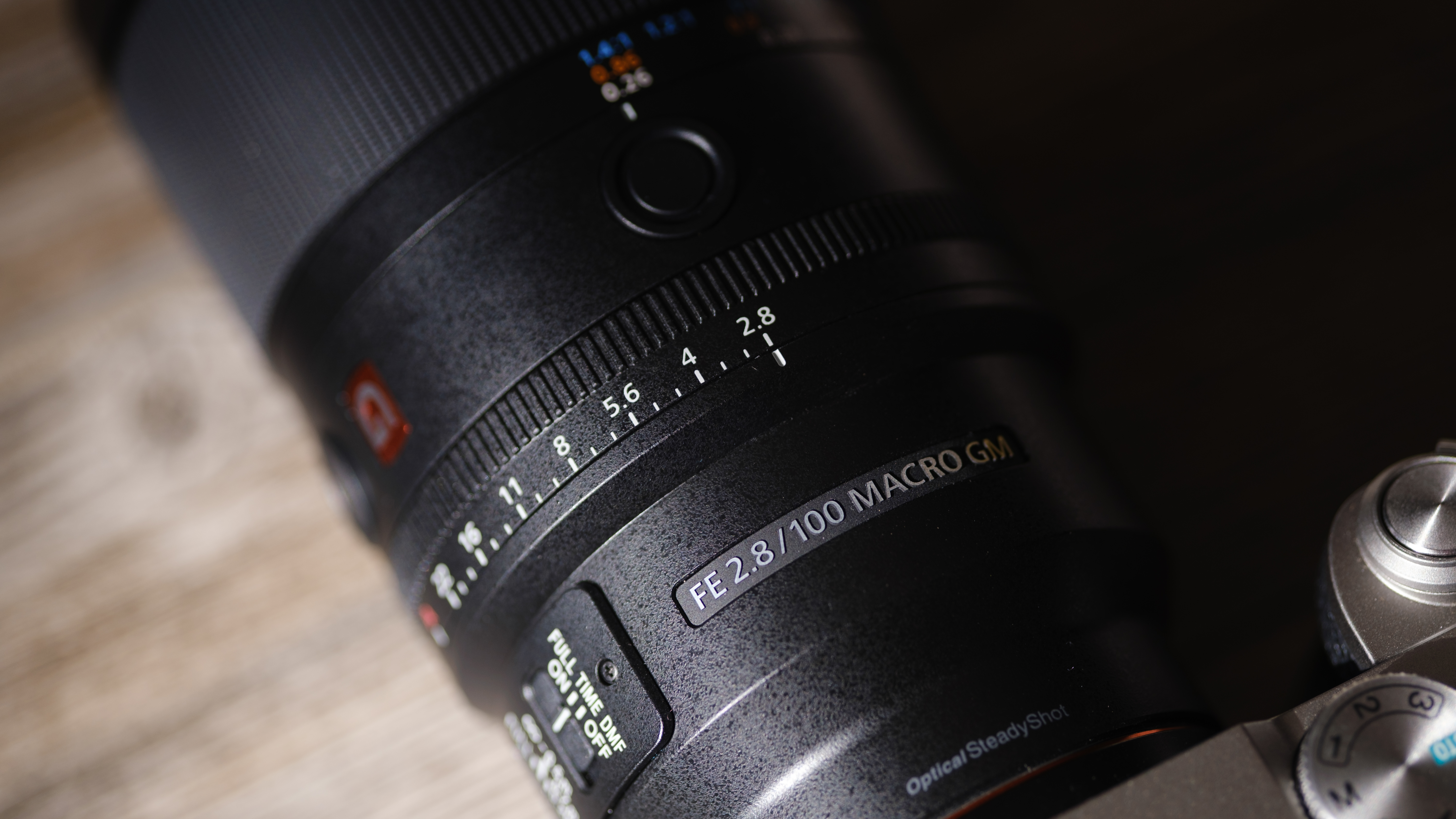 The Sony FE 100mm f/2.8 Macro GM OSS on a wood background