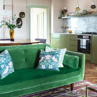 Green sofa with cushions in dark wood living room and kitchen