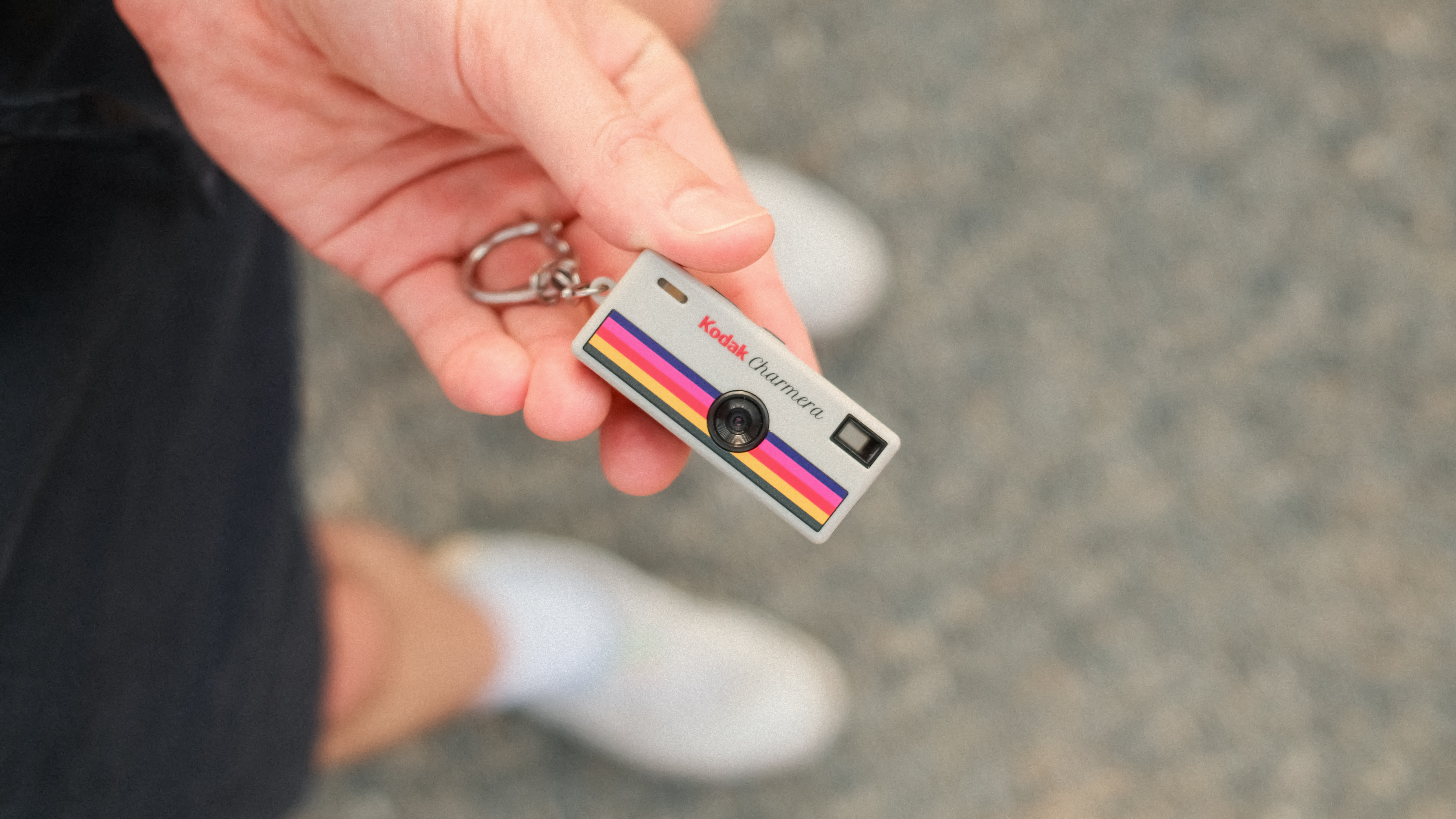 Close-up of a Kodak Charmera miniature camera keychain held in one hand.