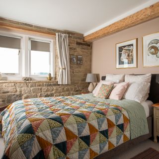 cottage bedroom with exposed stone wall, patchwork bed quilt