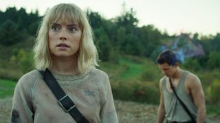 A still of Daisy Ridley as Viola Eade and Tom Holland as Todd Hewitt in Chaos Walking, as they both look worried in the countryside.