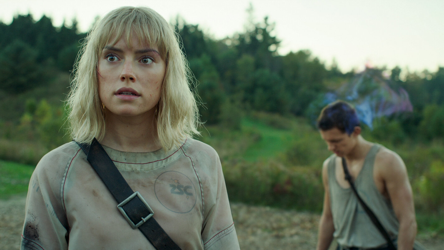 A still of Daisy Ridley as Viola Eade and Tom Holland as Todd Hewitt in Chaos Walking, both looking worried in the countryside.