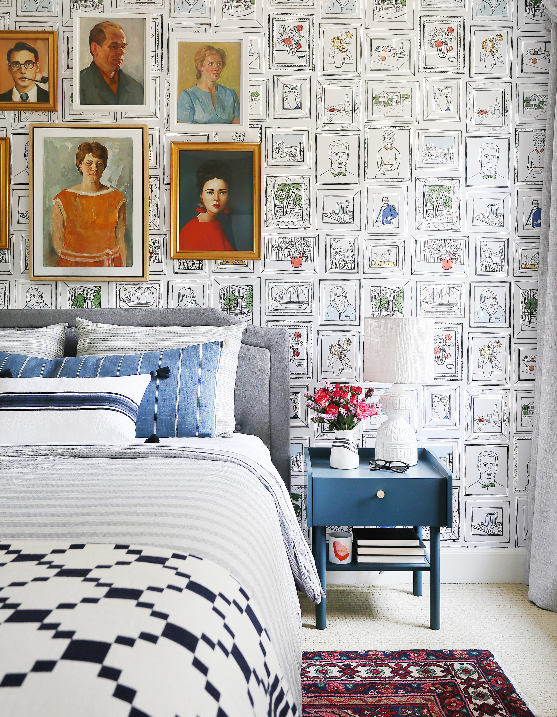 Chasing Paper portrait wallpaper in bedroom with grey upholstered bed frame and blue side table