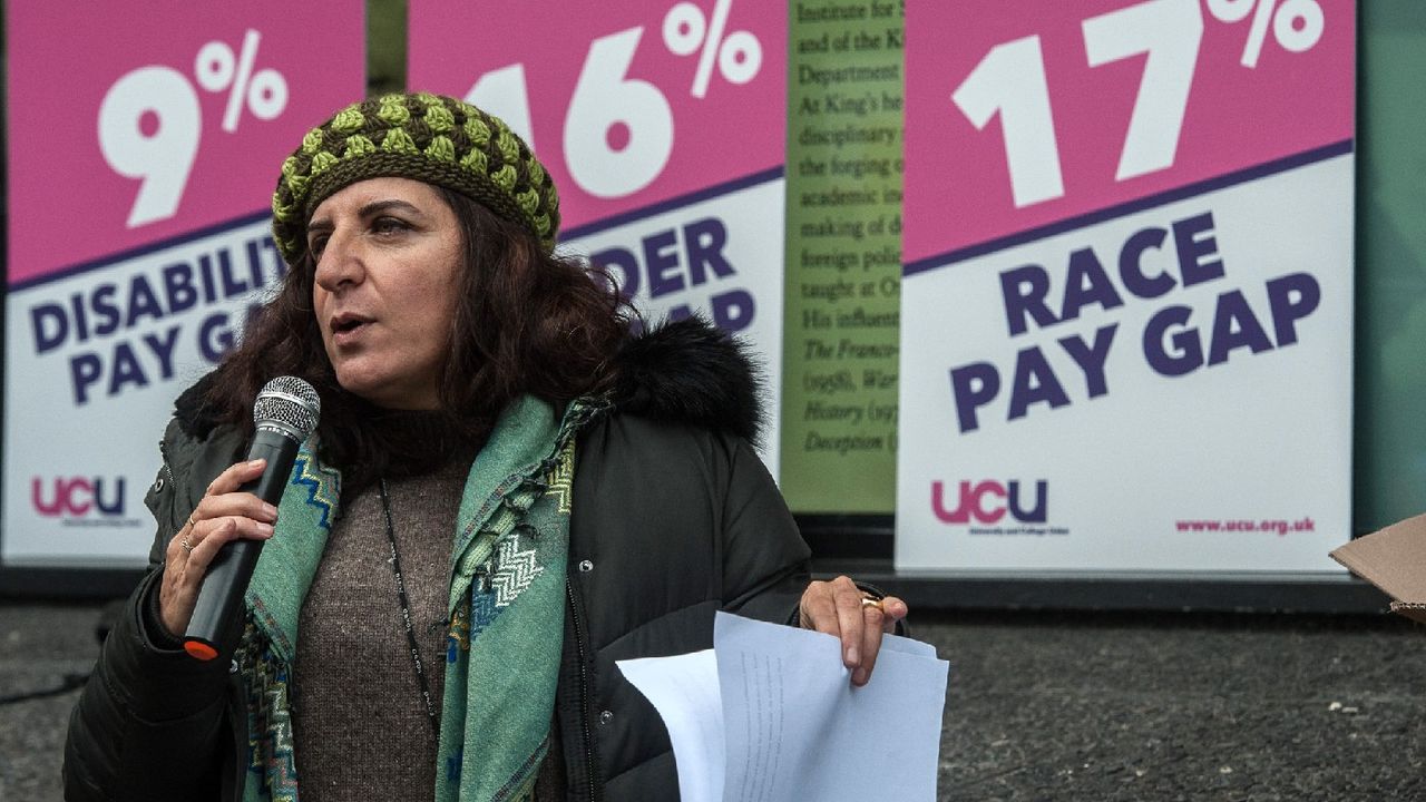 Woman protesting in front of signs about race and gender pay gaps