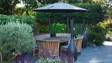 Wooden patio funiture under a black cantilevered umbrella