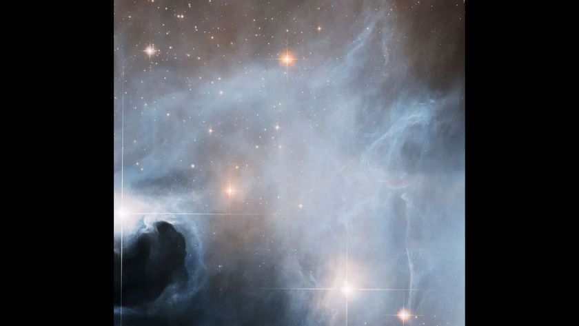 Photo numerous bright stars in space covered in think swirls of gray and white clouds. 