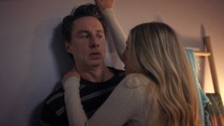 J.D. looking uncomfortable while his date Lily is holding him against a wall in Scrubs