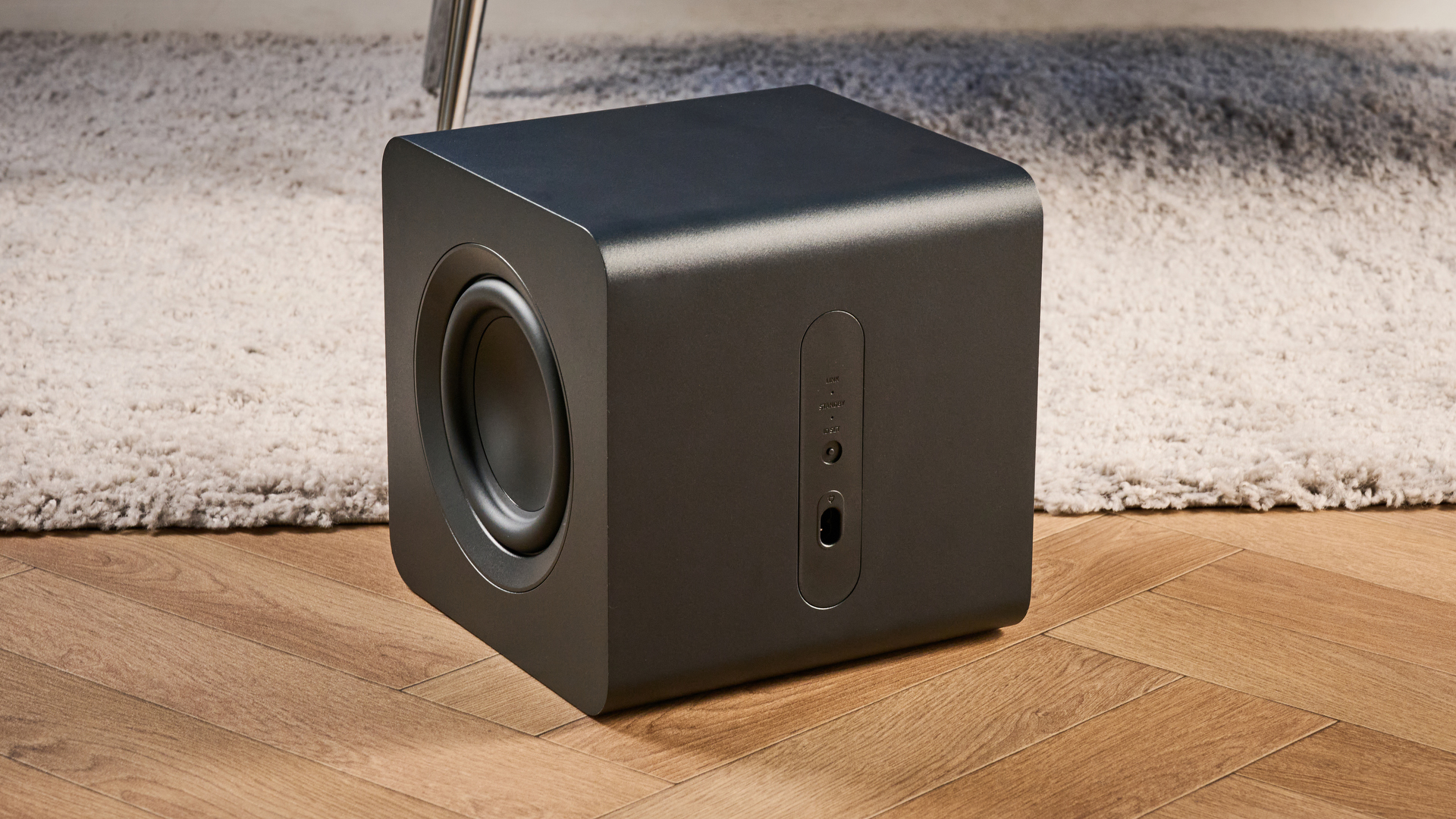 the samsung qs750f soundbar with two rear surround speakers and subwoofer photographed against a blue background and a TV