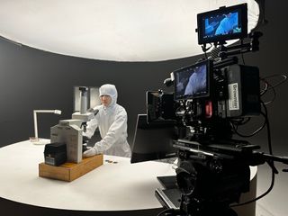 person looking at 3D printed tiny model through a microscope