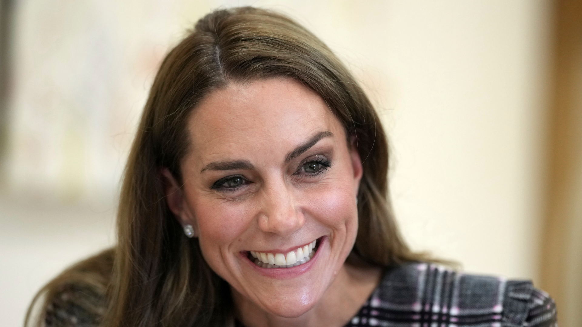 Kate Middleton smiling in a plaid dress