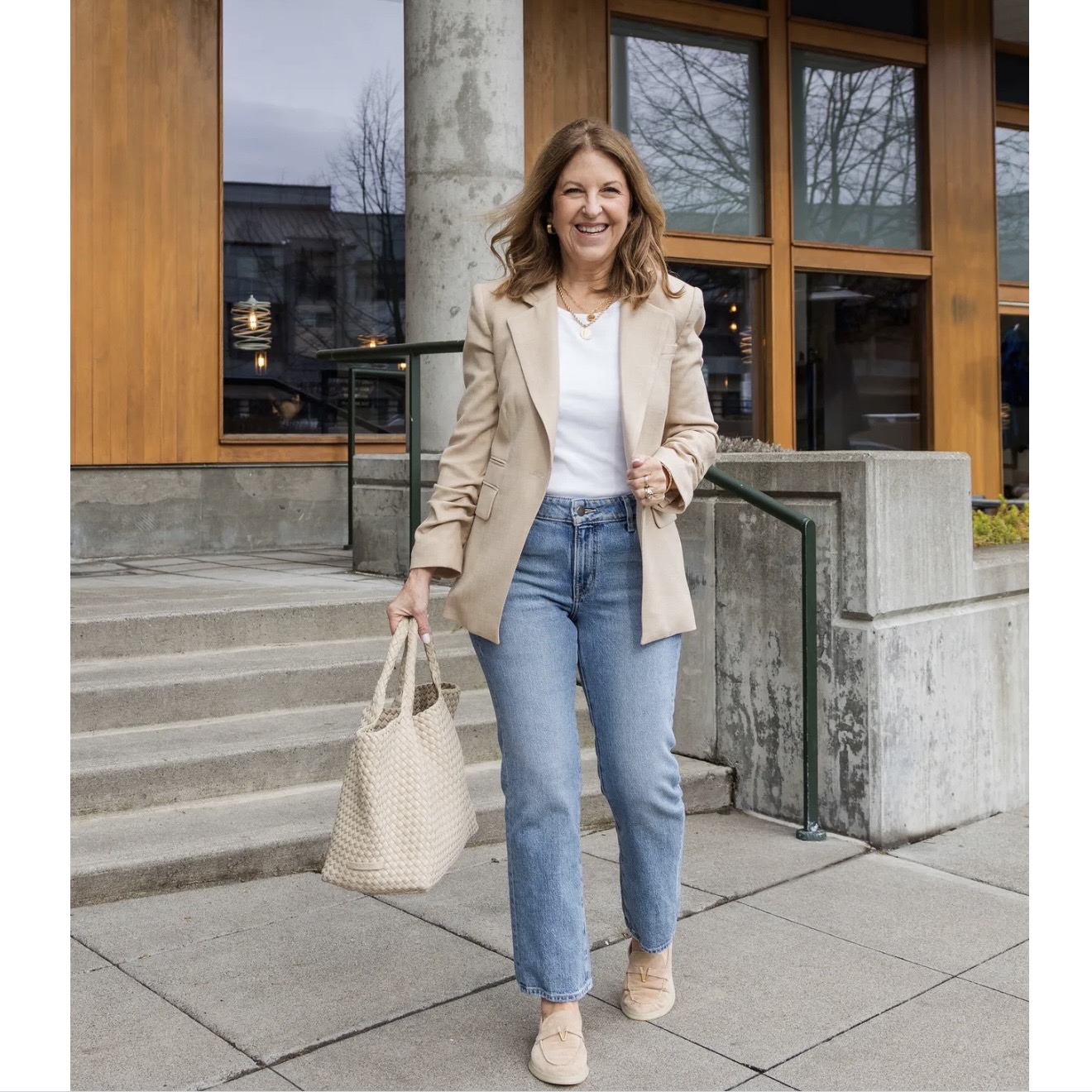 A former VIP Nordstrom stylist wearing a tan blazer over a white tee, jeans, and tan loafers.