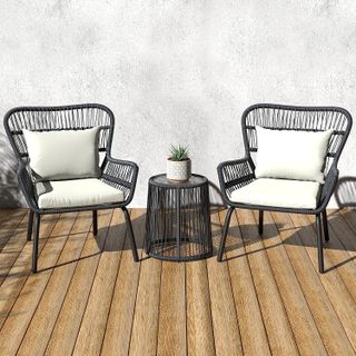 two grey woven chairs with cream cushions with a small round grey table in the middle