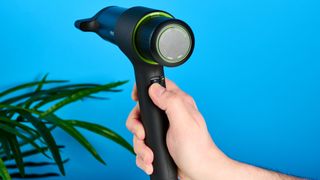 the heist 3.0 men's hair dryer in black with a bright green ring and magnetic attachment photographed against a blue background