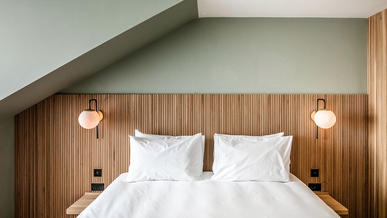 An example of a Mollie&#039;s hotel room in Oxfordshire, United Kingdom with green wall paint, double bed with mattress and pillows, wood paneling and bedside lighting fixtures