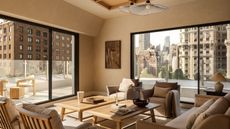 A neutral living room in a penthouse with a balcony running around it with a glass balustrade with two matching wood coffee tables in the center of mirroring armchairs and a sofa
