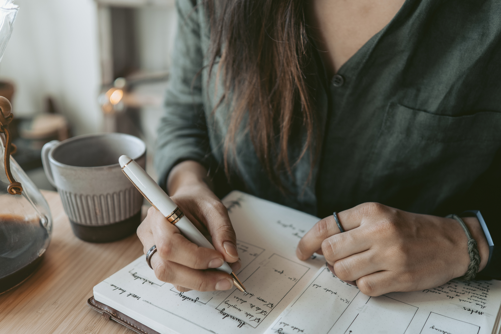 A woman taking notes in her planner at her desk.