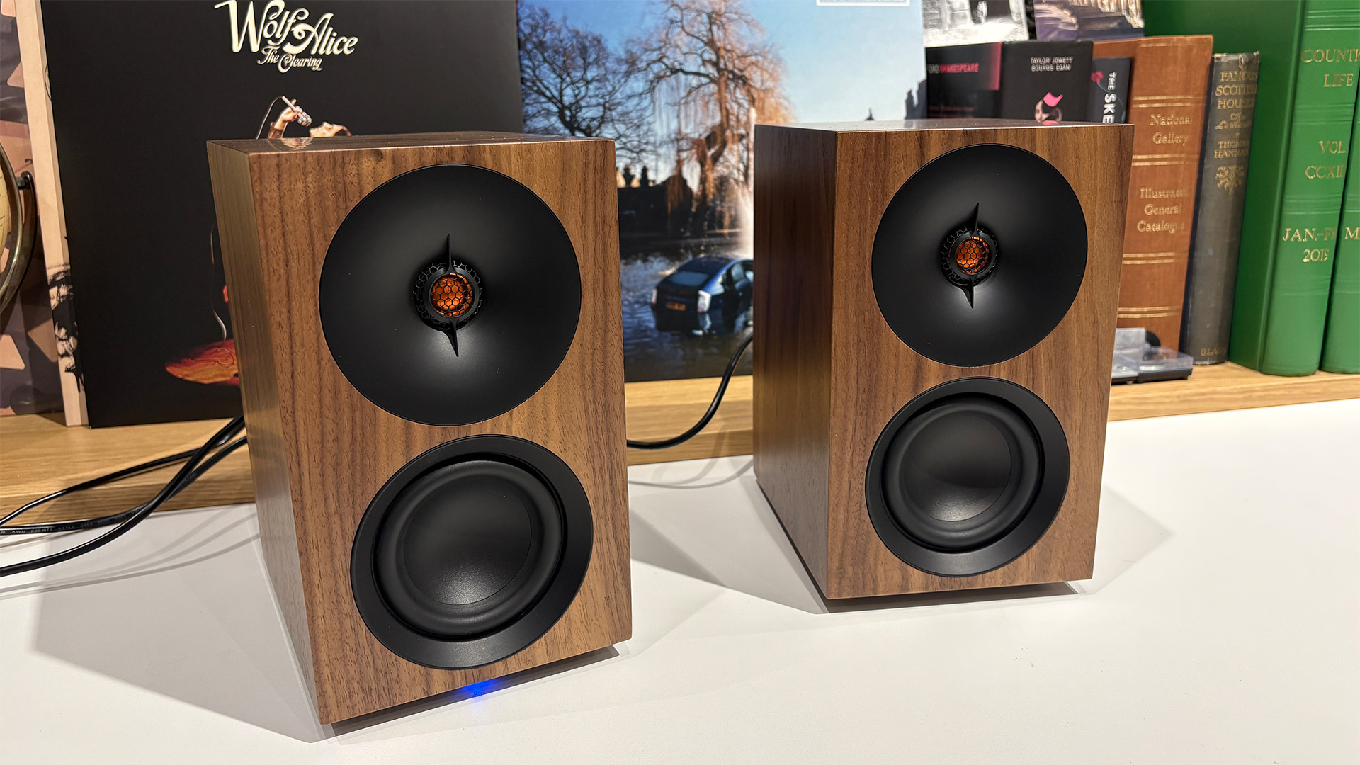 Cambridge Audio L/R S desktop speakers on white surface in front of busy bookcase