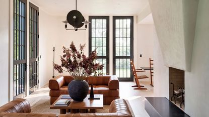 a living room with an interesting chandelier and tan sofas