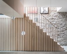 A stair railing idea by David Money in his own home using plywood, against painted exposed brick wall 