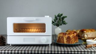 A toaster oven preheating with nothing inside next to bread