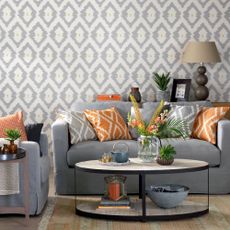 Grey living room with geometric wallpaper, grey sofas and orange accents