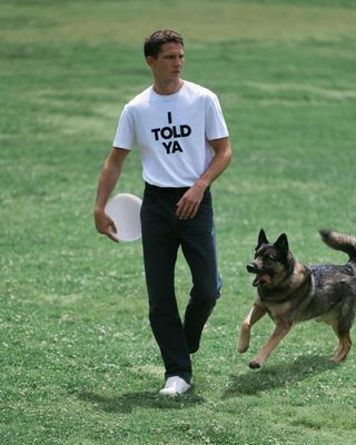 Man in Loewe ’I Told Ya’ T-shirt holding frisbee with dog outside