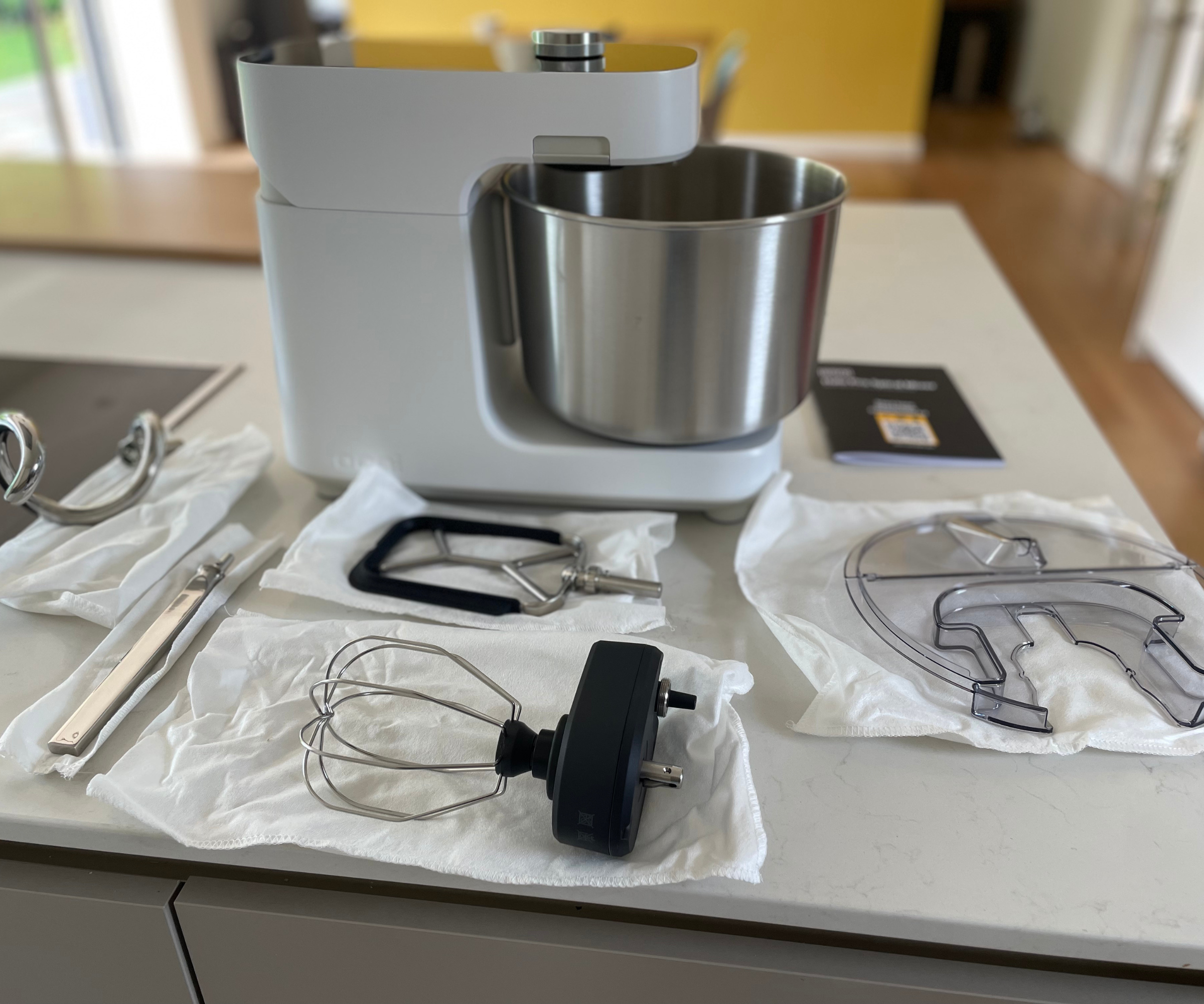 Ooni Halo Pro Spiral Mixer surrounded by the attachments, like whisks and paddles