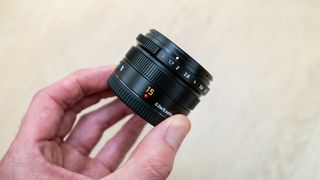 Panasonic Leica Summilux DG 15mm f/1.7 ASPH being held in a hand.