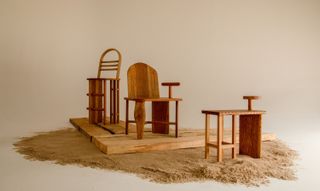 In a cream-shaded room, a series of furniture objects made in wood are placed on top of a swathe of sand.