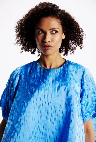 Gugu Mbatha-Raw wears a blue baby doll dress looking to the side.