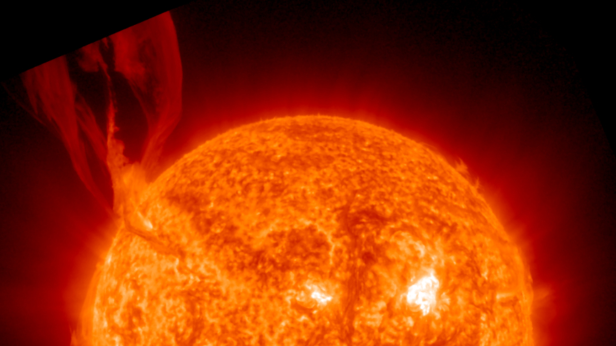 a large fiery looking filament erupts from the upper left corner of the sun and reaches far into space.