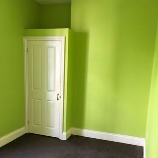 bedroom with olive green walls and white wooden door