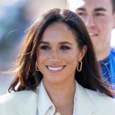 Meghan Markle looks away from the camera and smiles