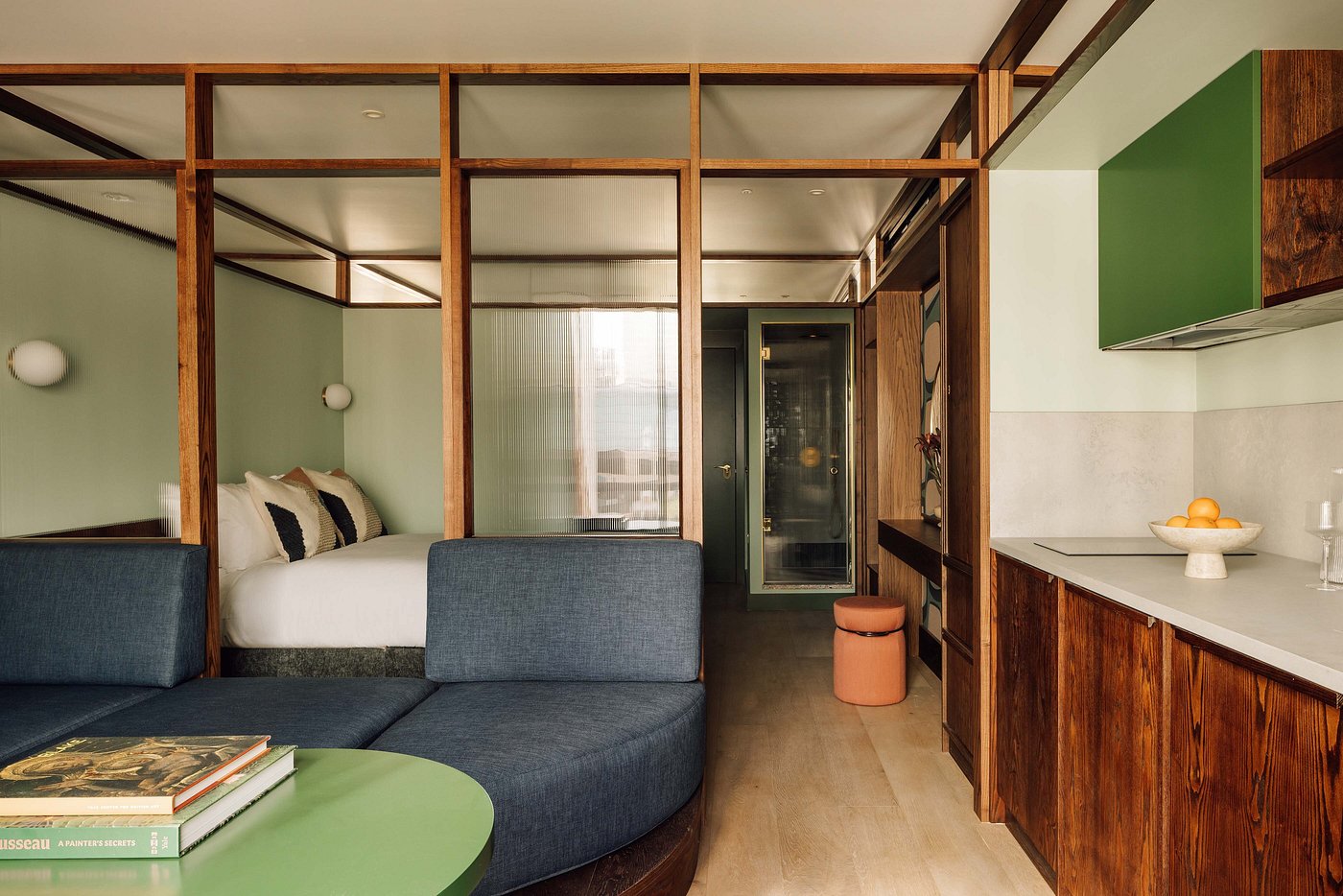 Interior shots of a design hotel decorated with pale woods, plants, industrial-chic furniture, and warm lighting, with spherical sconces and pendant lamps.