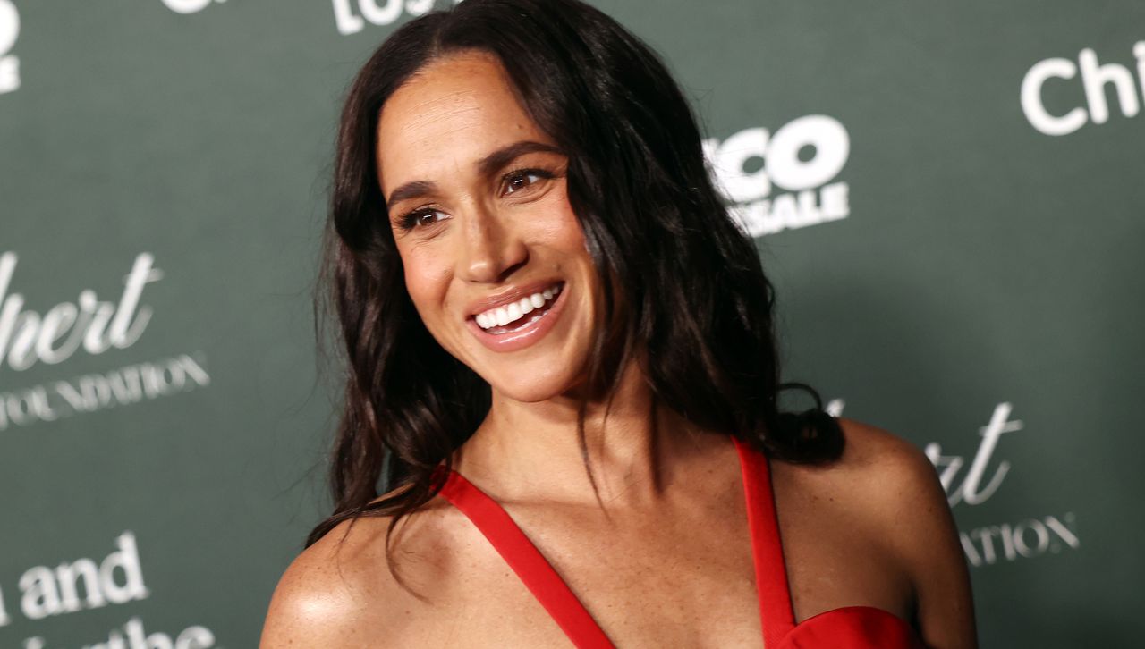 Meghan Markle on a red carpet wearing a red dress with wavy hair