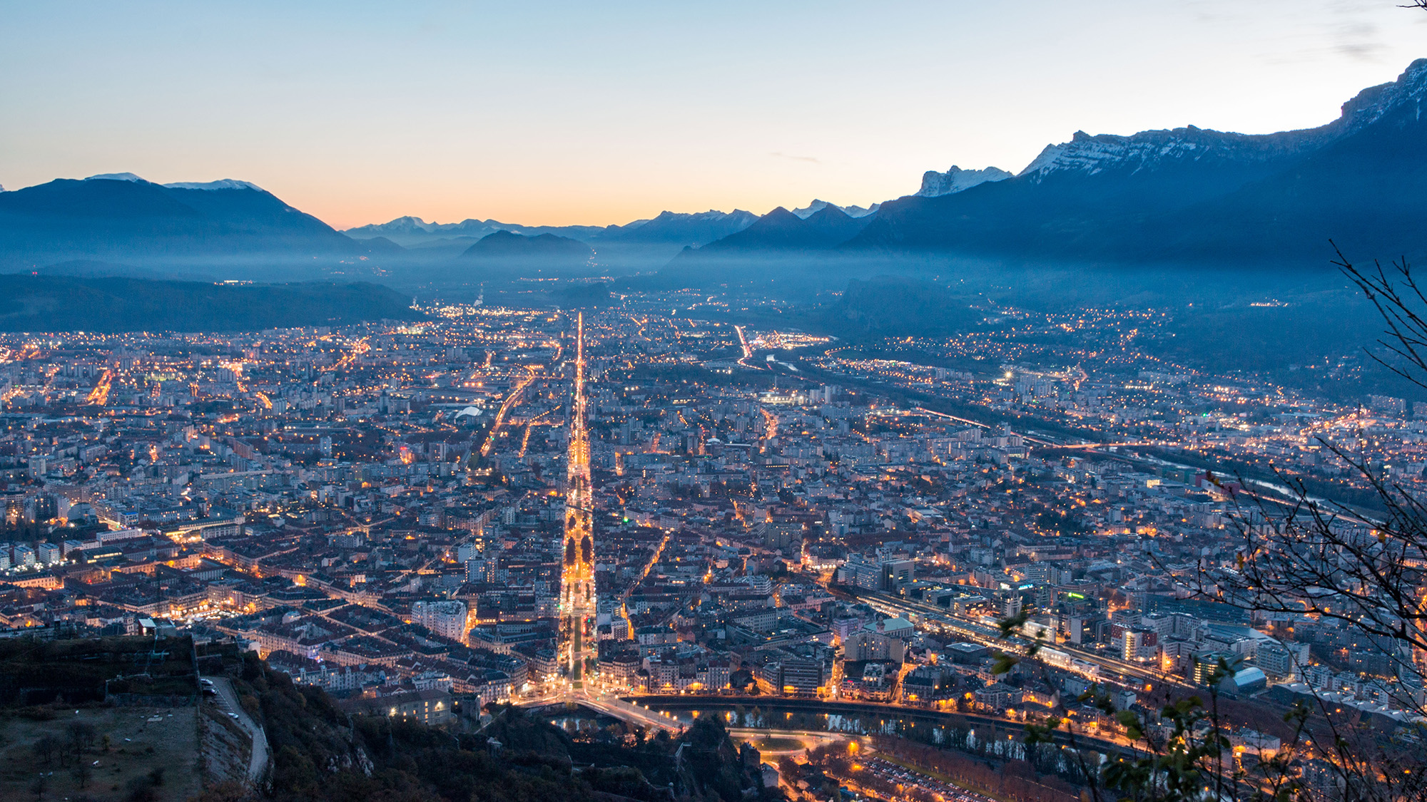 An evening cityscape of Grenoble with the Alps in the background