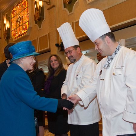 Queen Elizabeth shaking hands with two chefs