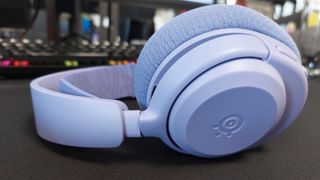 The SteelSeries Arctis Nova 3 X seen on a desk. This is the Lavender colourway.