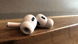 The AirPods Pro 2 buds pictured out of their charging case on a wooden surface