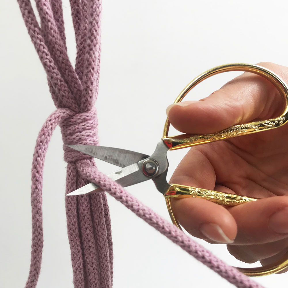 hand cutting purple cord with wrapped knots