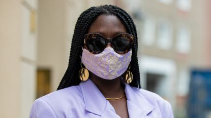 Lois Opoku is seen wearing face mask Nada Dehni, purple blazer Pyer Moss, Bottega Veneta bag in turquoise, Zara pants with graphic print, Fendi sunglasses, Prada sandals on September 04, 2020 in Berlin, Germany