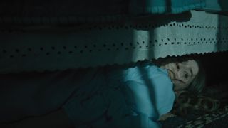 Kaitlyn Dever hiding under a bed in No One Will Save You