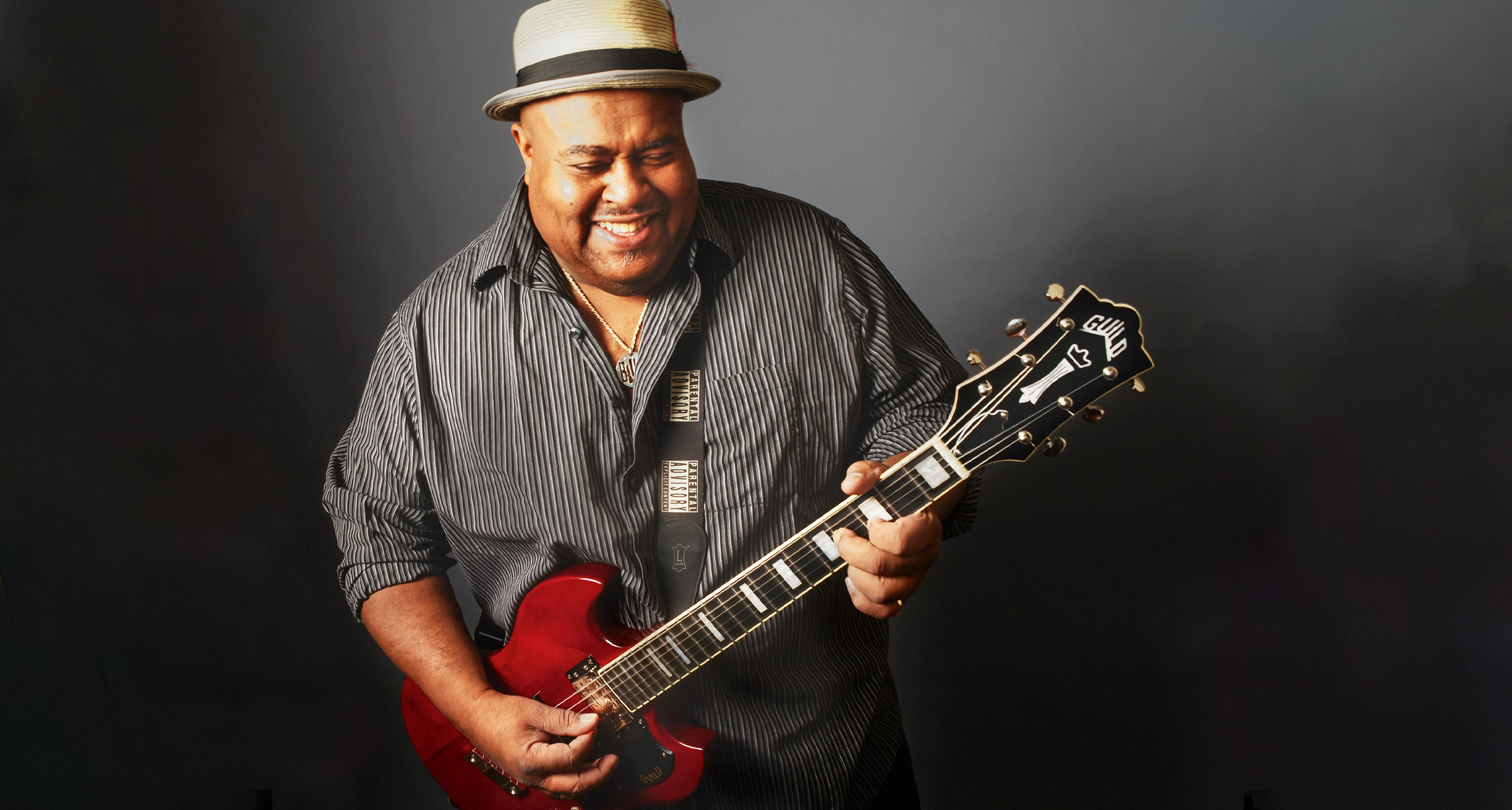 Larry McCray smiles as he plays his red Guild Polara