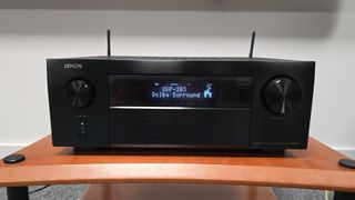 Denon AVC-X6800H from front showing display, on wooden rack