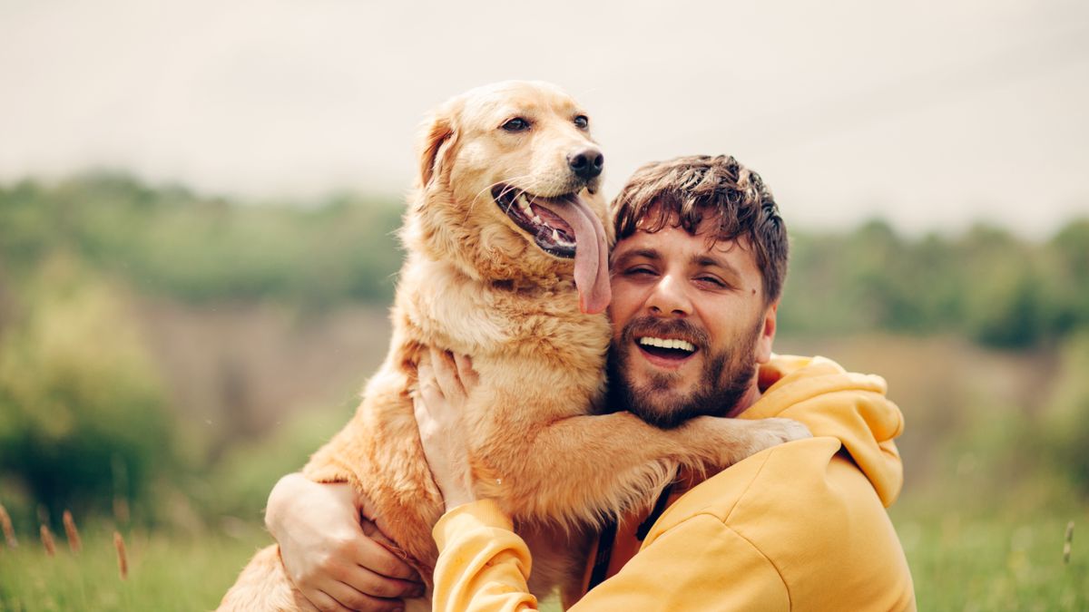 Man hugging his golden retriever outside