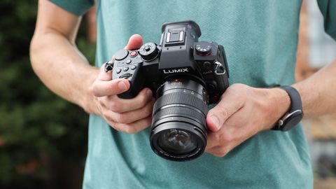 Panasonic Lumix GH7 held in the hands of a person wearing a green t-shirt