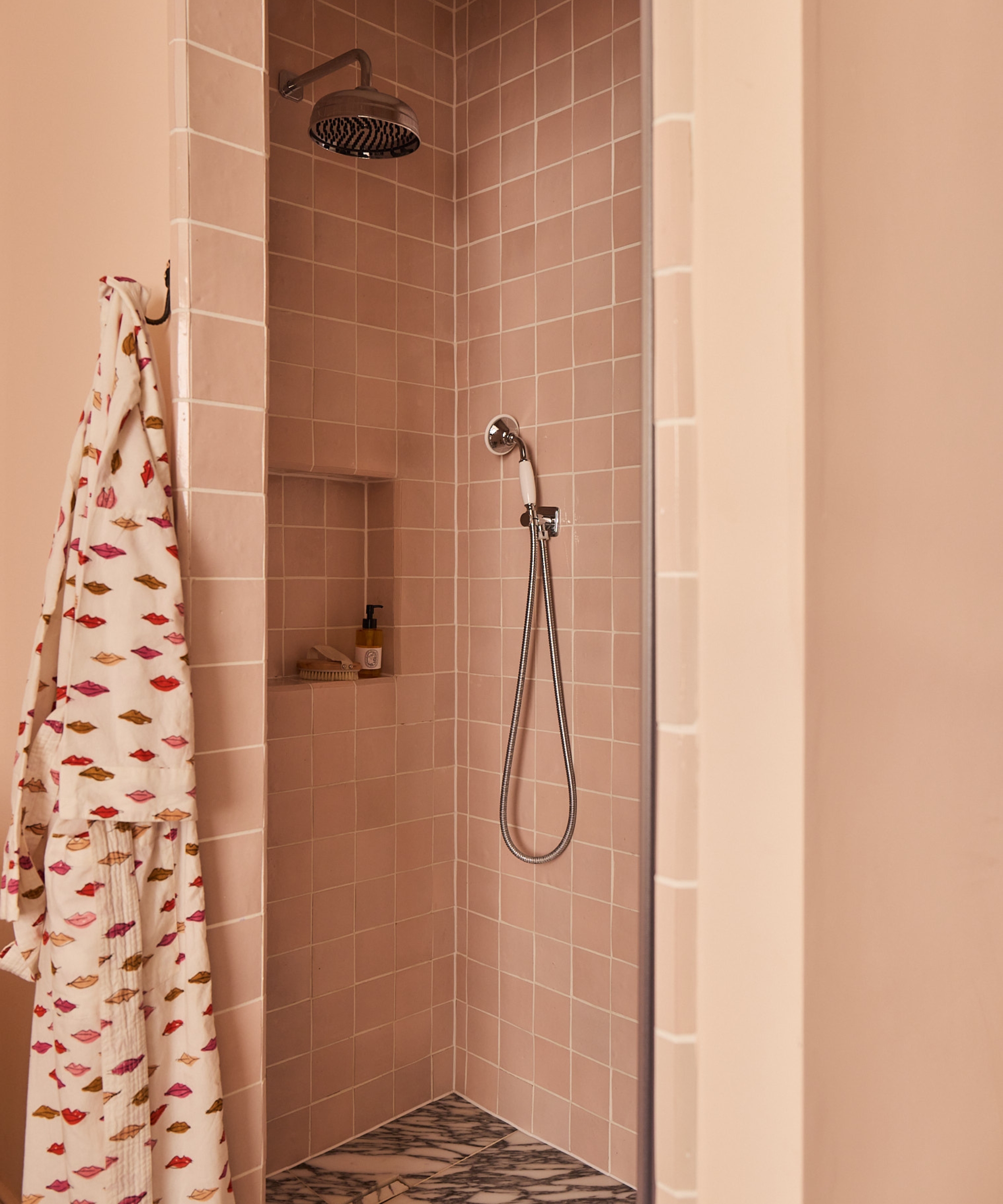 A small shower room drenched in pink tiles and a marble floor
